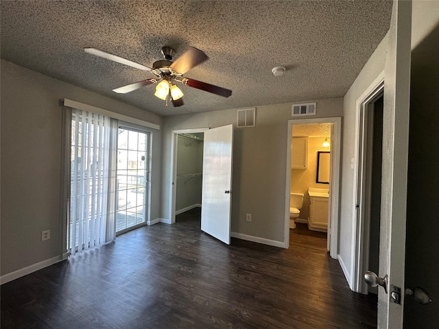 unfurnished bedroom with dark wood-style floors, visible vents, a textured ceiling, and baseboards