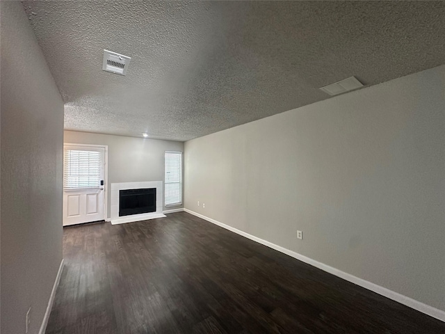 unfurnished living room with visible vents, a fireplace, dark wood-type flooring, and baseboards