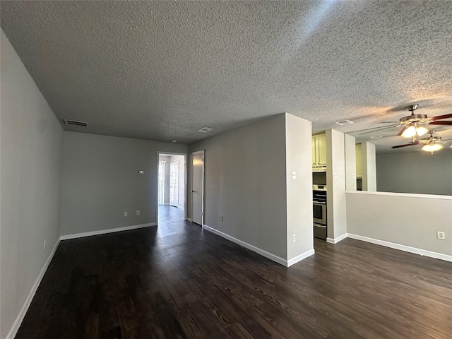 unfurnished room with dark wood finished floors, visible vents, baseboards, and ceiling fan