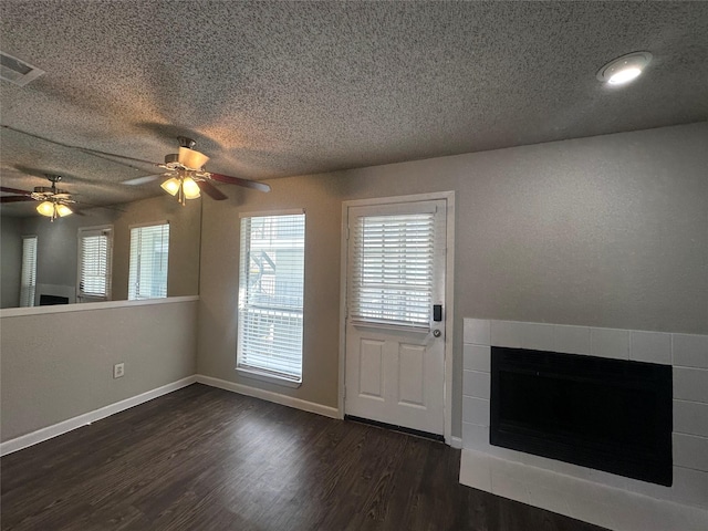 unfurnished living room featuring dark wood finished floors, a textured ceiling, visible vents, and a tile fireplace