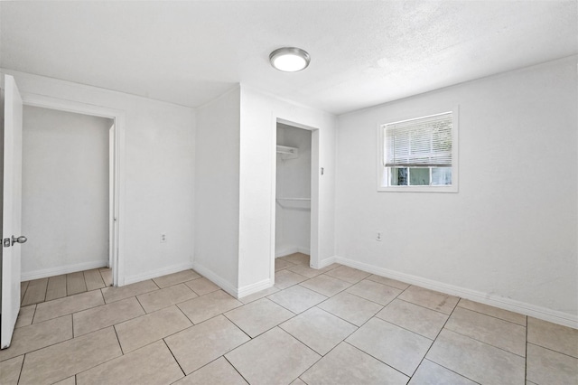 unfurnished bedroom with light tile patterned flooring, baseboards, and a closet