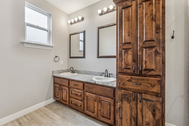 full bath with a sink, baseboards, and double vanity