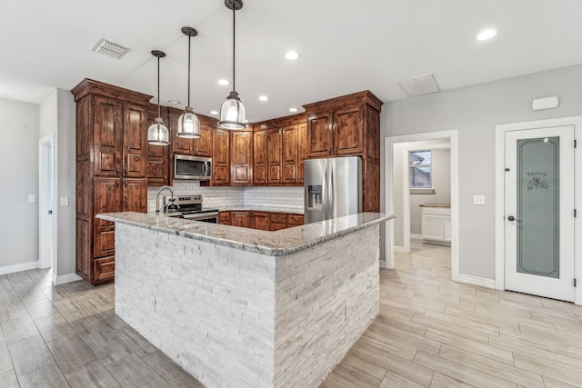 kitchen featuring light stone countertops, visible vents, stainless steel appliances, decorative backsplash, and pendant lighting