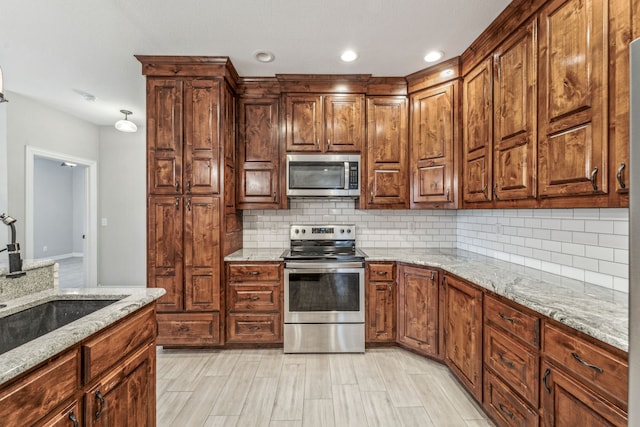 kitchen with light stone counters, recessed lighting, a sink, appliances with stainless steel finishes, and backsplash