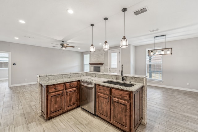 kitchen featuring visible vents, open floor plan, dishwasher, a fireplace, and a sink