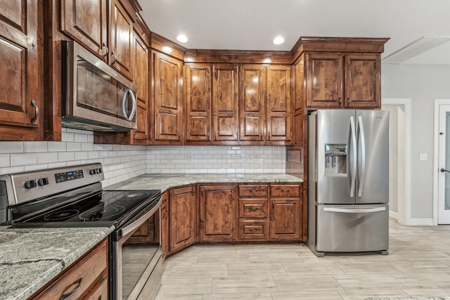 kitchen with baseboards, light stone countertops, tasteful backsplash, and appliances with stainless steel finishes