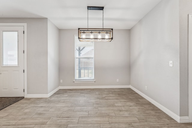 unfurnished dining area with baseboards and wood tiled floor