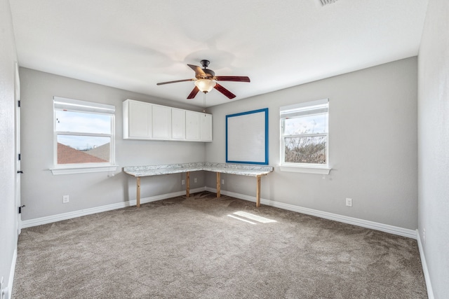 interior space with carpet floors, baseboards, a wealth of natural light, and built in study area