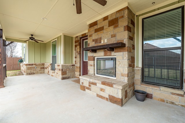 view of patio featuring an outdoor stone fireplace, a ceiling fan, and fence