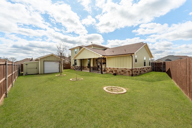 back of house with an outdoor fire pit, a fenced backyard, an outbuilding, stone siding, and a patio