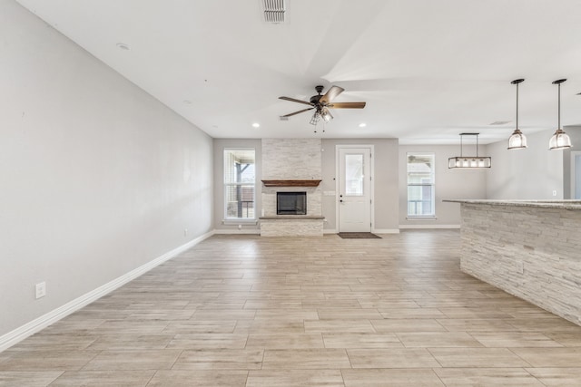 unfurnished living room featuring visible vents, a fireplace, ceiling fan, and wood tiled floor