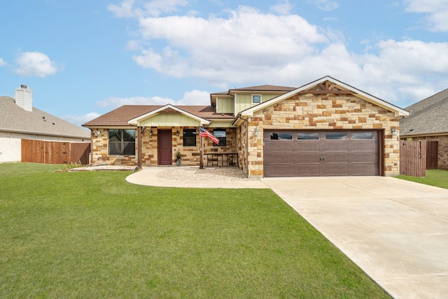 view of front of property featuring a front lawn, fence, driveway, stone siding, and an attached garage