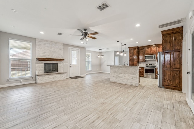 kitchen featuring open floor plan, a fireplace, visible vents, and stainless steel appliances