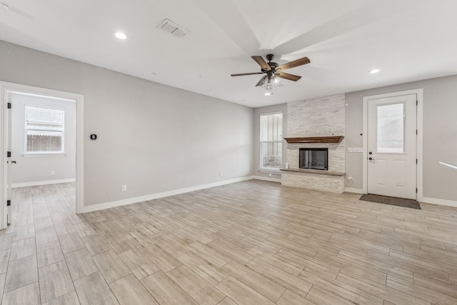 unfurnished living room with visible vents, baseboards, light wood-type flooring, a fireplace, and a ceiling fan