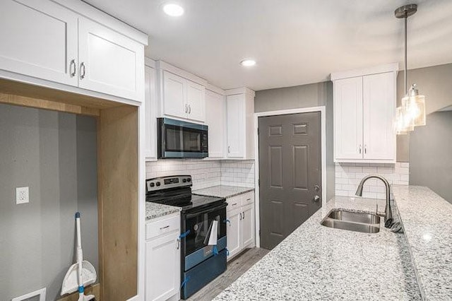 kitchen with a sink, light stone countertops, range with electric cooktop, and white cabinetry