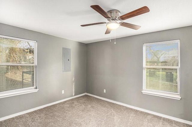 carpeted empty room with electric panel, baseboards, and ceiling fan