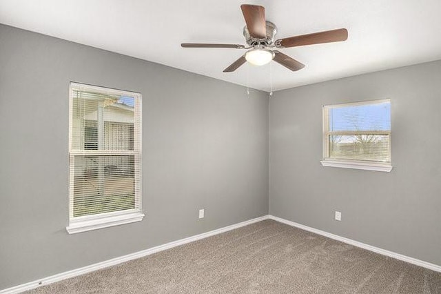 carpeted spare room with ceiling fan and baseboards