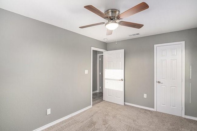 unfurnished bedroom featuring visible vents, light colored carpet, a ceiling fan, and baseboards