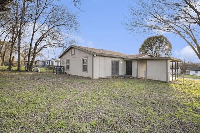 rear view of property featuring a lawn and fence