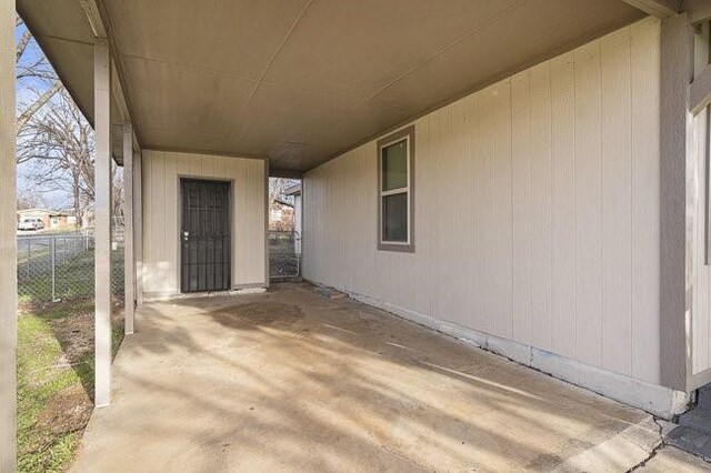 view of patio / terrace with an attached carport and fence