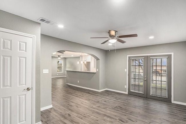 unfurnished room featuring wood finished floors, arched walkways, visible vents, and a wealth of natural light