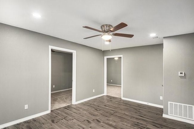 unfurnished room featuring dark wood finished floors, baseboards, visible vents, and ceiling fan