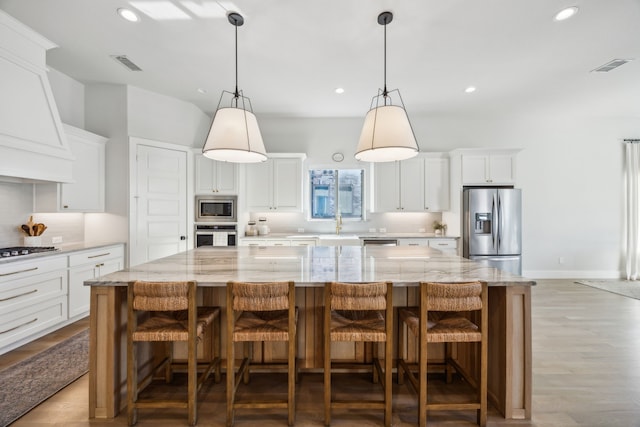 kitchen featuring visible vents, white cabinets, stainless steel appliances, and custom range hood