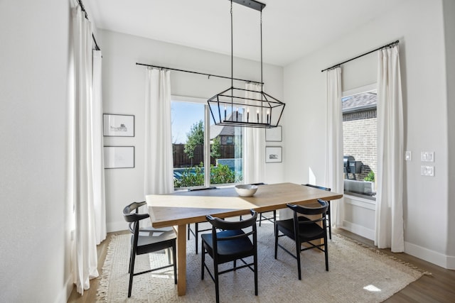 dining area with baseboards, an inviting chandelier, and wood finished floors