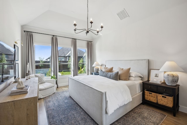 bedroom with visible vents, baseboards, vaulted ceiling, an inviting chandelier, and wood finished floors