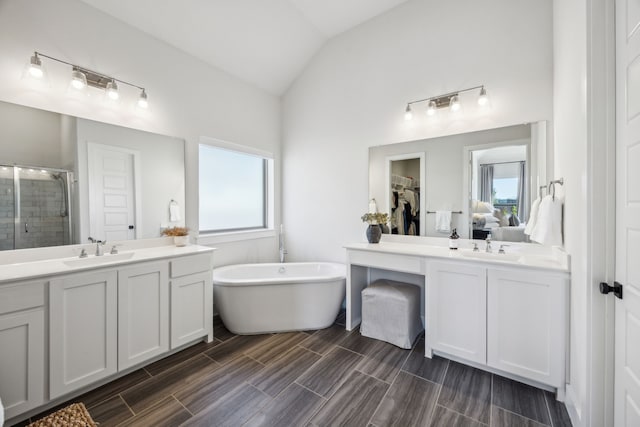 bathroom with a stall shower, two vanities, lofted ceiling, and a sink