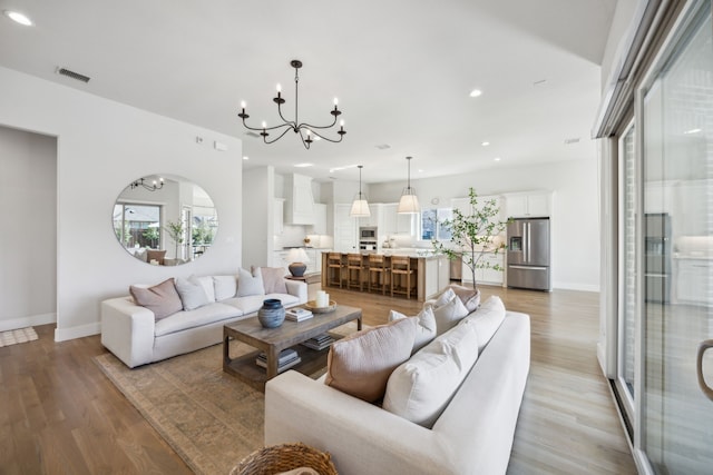 living area featuring a notable chandelier, recessed lighting, baseboards, and light wood-style floors