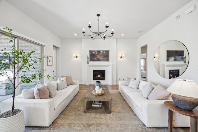 living room with a glass covered fireplace, recessed lighting, and an inviting chandelier