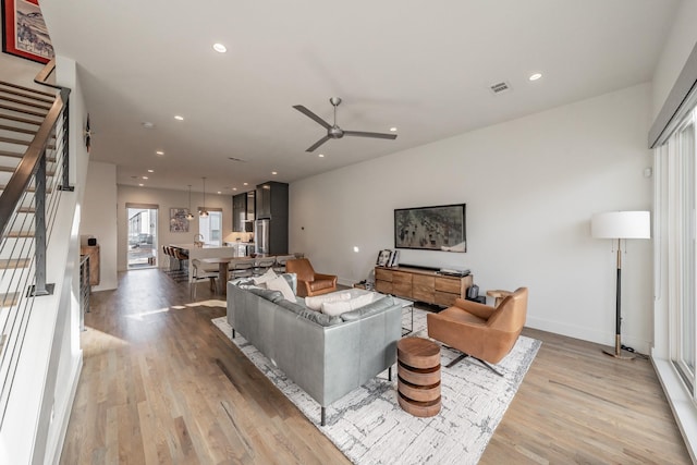 living area featuring recessed lighting, visible vents, light wood-style flooring, and stairs