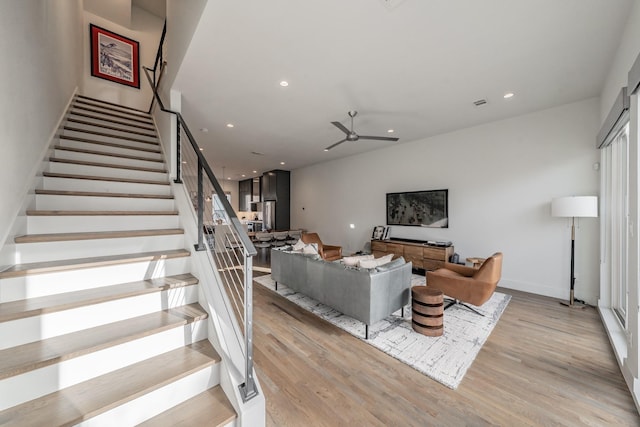 living room featuring light wood finished floors, recessed lighting, stairs, and a ceiling fan