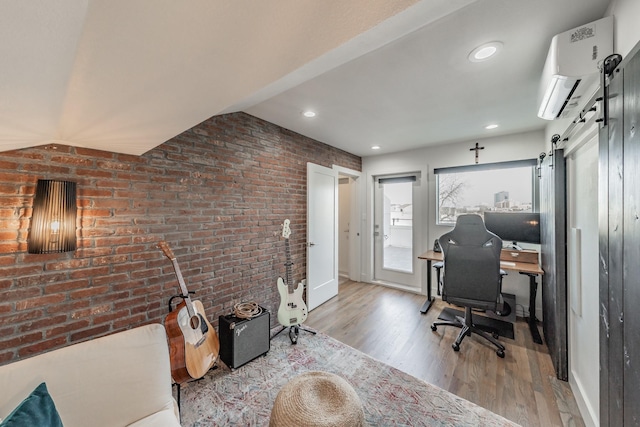 office space with a wall mounted air conditioner, wood finished floors, recessed lighting, a barn door, and brick wall