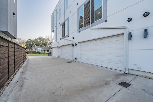 exterior space featuring an attached garage, fence, driveway, and stucco siding