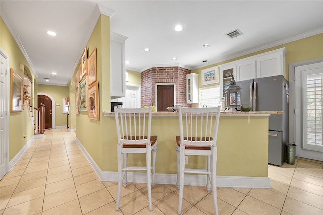 kitchen featuring arched walkways, light tile patterned flooring, crown molding, and freestanding refrigerator