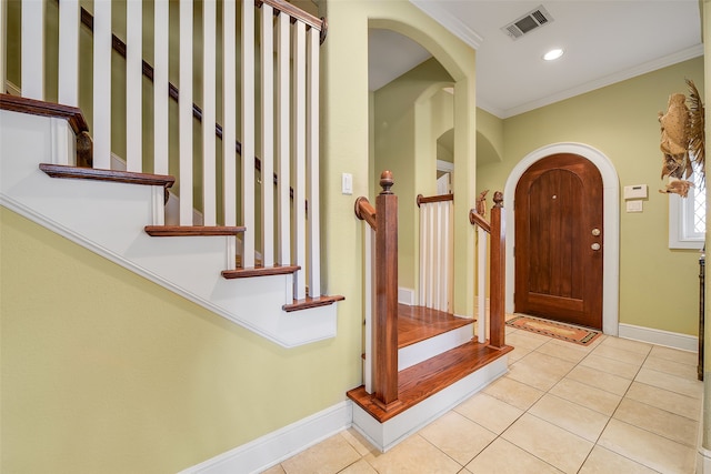 entrance foyer featuring visible vents, ornamental molding, arched walkways, light tile patterned floors, and baseboards