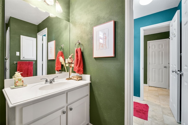 bathroom with vanity, baseboards, and a textured wall