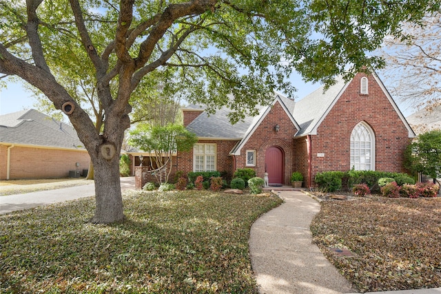 view of front facade with brick siding and a shingled roof