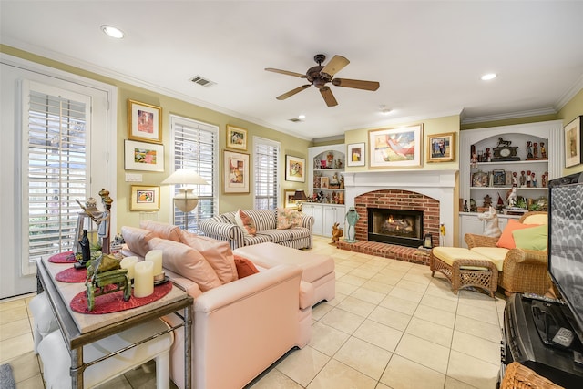 living area featuring visible vents, ornamental molding, built in features, light tile patterned flooring, and a brick fireplace