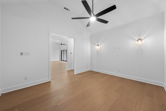 unfurnished room with visible vents, baseboards, high vaulted ceiling, and wood finished floors