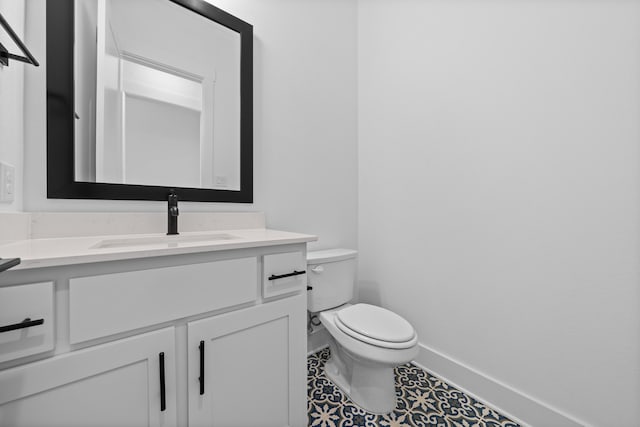 half bath featuring toilet, vanity, and baseboards