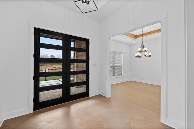 entryway featuring a wealth of natural light, baseboards, a raised ceiling, and an inviting chandelier