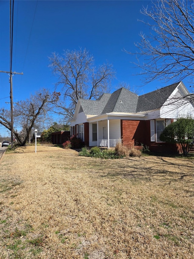 view of home's exterior featuring a lawn, brick siding, and a shingled roof