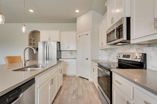 kitchen with a sink, light wood-style floors, appliances with stainless steel finishes, white cabinetry, and backsplash