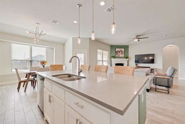 kitchen with a sink, visible vents, dishwasher, and a center island with sink