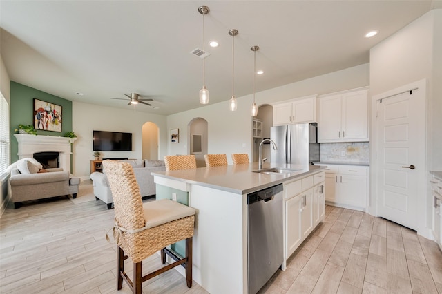 kitchen featuring visible vents, arched walkways, appliances with stainless steel finishes, a kitchen breakfast bar, and open floor plan