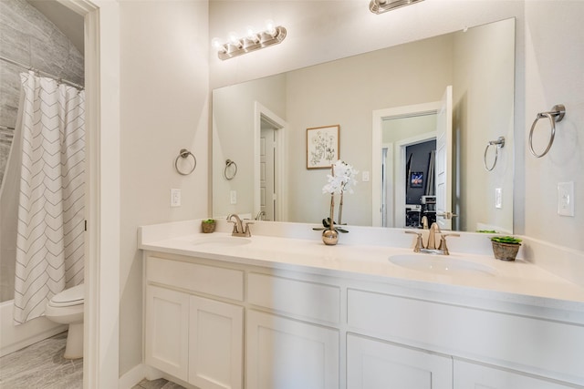 full bathroom with a sink, shower / bath combo with shower curtain, toilet, and double vanity