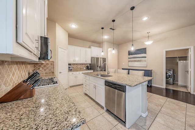 kitchen with a sink, washer / clothes dryer, light tile patterned floors, and stainless steel appliances